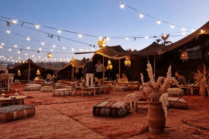 Illuminated desert camp at dusk with string lights